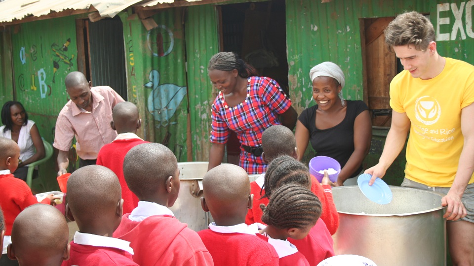 a volunteer assist with serving food at Excel school in the Nairbi slums